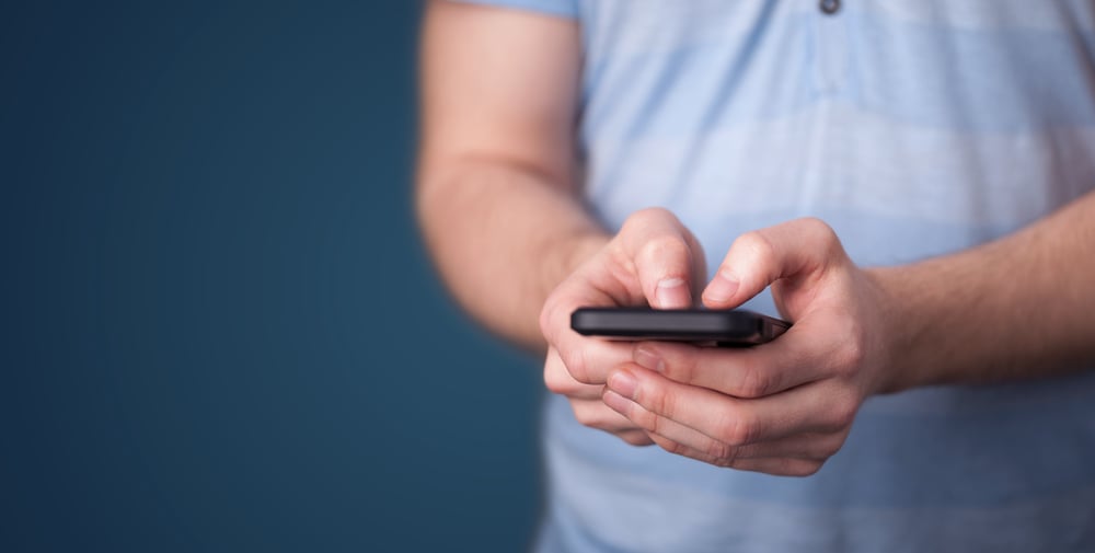 Man holding smarthphone in hand while typing